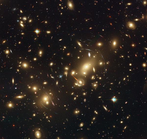 Ярчайшая галактика на этом изображении скопления <noindex><a target=_blank href=http://en.wikipedia.org/wiki/Abell_2218>Abell 2218</a></noindex> имеет вид оранжевой дуги. (Иллюстрация НАСА, ESA, Johan Richard.)